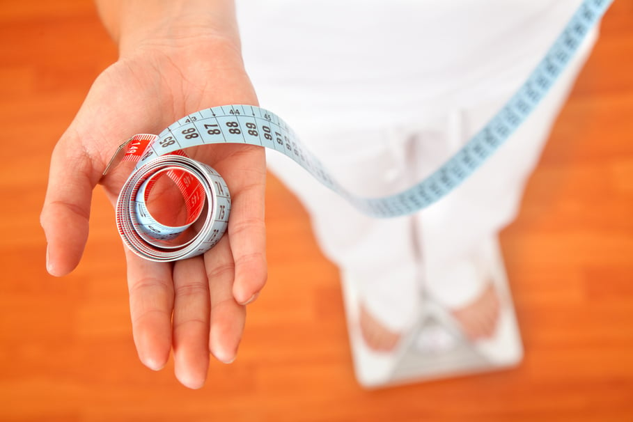 Woman on a scale with a measuring tape