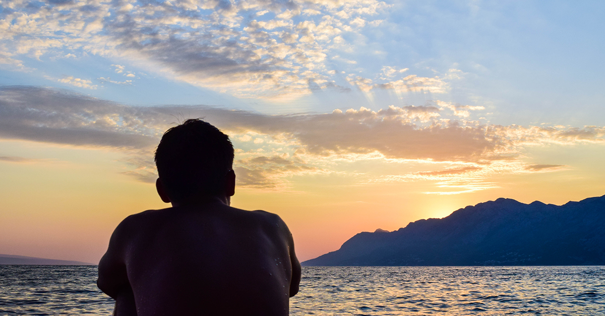 male-sitting-sunrise-beach-1200x628