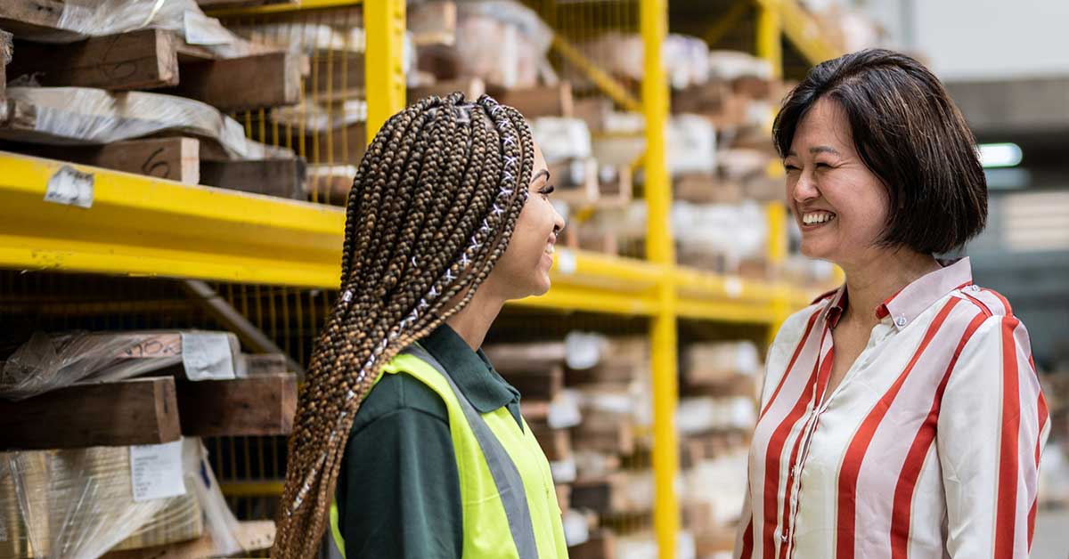 female-leader-smiling-with-employee-1200x628